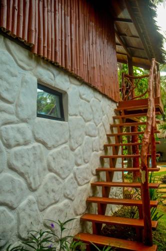 a stone house with a wooden staircase leading up to it at Camaya-an Paradise Beach Resort in Malabugas