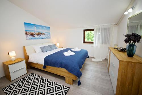 Schlafzimmer mit einem Bett mit blauer Decke in der Unterkunft Apartments Perkovic in Fažana