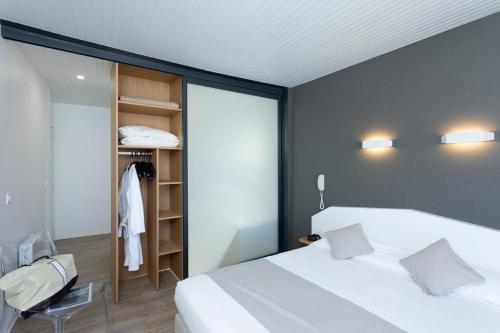 a bedroom with a large white bed and a closet at Hotel Les Dunes in La Tranche-sur-Mer