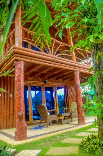 a house with a wooden roof with chairs and windows at Camaya-an Paradise Beach Resort in Malabugas