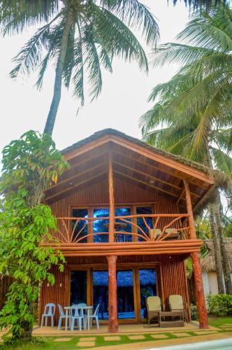 a wooden house with a patio and palm trees at Camaya-an Paradise Beach Resort in Malabugas
