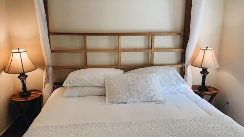 a bedroom with a white bed with two lamps at Caye Casa in San Pedro
