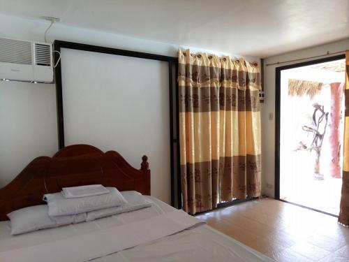 a bedroom with a bed and a large window at Camaya-an Paradise Beach Resort in Malabugas