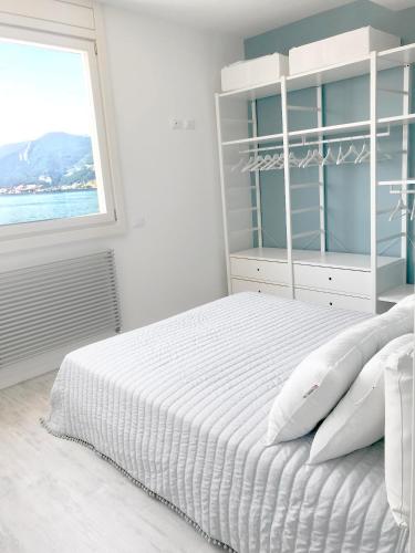 a white bedroom with a bed and a window at Iseo Vista Lago in Iseo