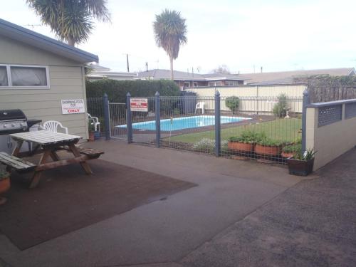 un patio trasero con una valla y una piscina en Cambrian Lodge Motel, en Cambridge