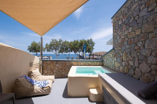 a patio with a swimming pool next to a stone wall at Cyclops Beach Apartments in Perivolos