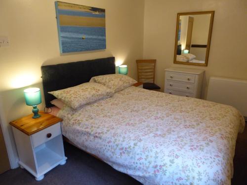 a bedroom with a bed and a table with two lamps at The Old Shippon in Bude