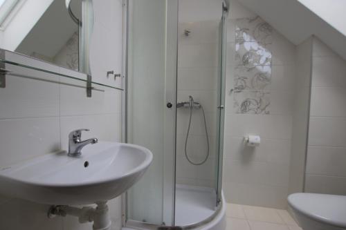 a white bathroom with a sink and a shower at Pokoje i Restauracja Jantarowa in Jantar