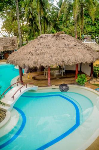 a large swimming pool with a thatch hut at Camaya-an Paradise Beach Resort in Malabugas