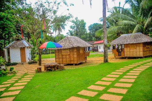 a group of huts and an umbrella in a yard at Camaya-an Paradise Beach Resort in Malabugas