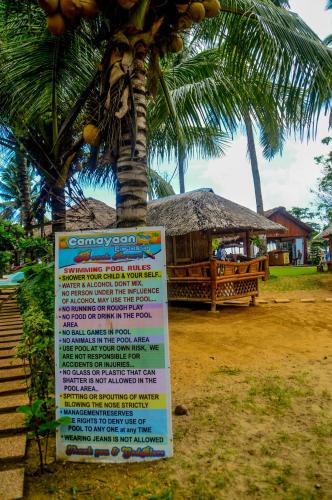 a sign in front of a palm tree with a building at Camaya-an Paradise Beach Resort in Malabugas