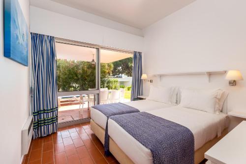 a bedroom with a large bed and a large window at Apartamentos Turisticos Pinhal Da Marina in Vilamoura