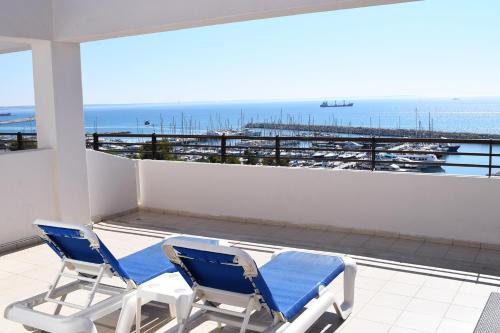 two blue chairs on a balcony with a view of the ocean at Sun Hall Beach Hotel Apartments in Larnaka