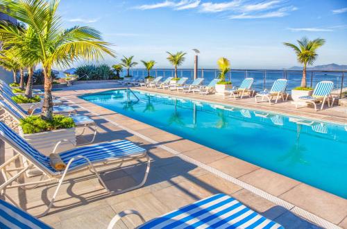 uma piscina com cadeiras e o oceano ao fundo em Windsor Barra Hotel no Rio de Janeiro