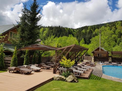 eine Terrasse mit Tischen und Stühlen neben einem Pool in der Unterkunft Villa Nova in Tatariw