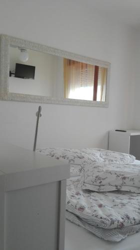 a white bedroom with a bed and a mirror at B&B Casa Sartori in Malcesine