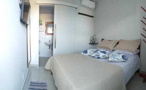 a white bedroom with a bed and a bathroom at Airport Pousada in Cabo Frio