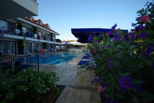 a swimming pool with chairs and flowers next to a building at Rota Hotel in Dalyan