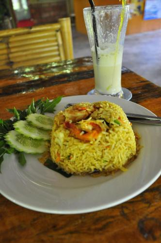 a plate of rice with shrimp and cucumbers and a drink at Lanta Pearl Beach Resort in Ko Lanta