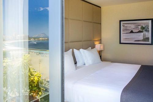 a hotel room with a bed and a large window at Windsor California Copacabana in Rio de Janeiro