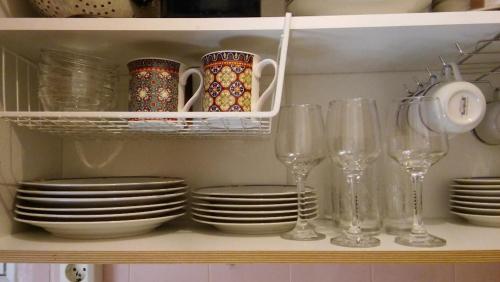 a shelf with plates and wine glasses in a kitchen at CHRYSSA - ΧΡΥΣΑ in Patra
