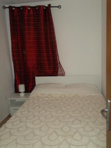 a bedroom with a bed and a red curtain at Hodak Apartment in Nerezine
