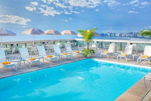 uma piscina no topo de um edifício com cadeiras e guarda-sóis em Windsor Excelsior Copacabana no Rio de Janeiro