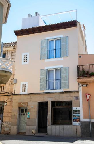 a building with blue shutters on it at Can Serol Apartaments in Capdepera