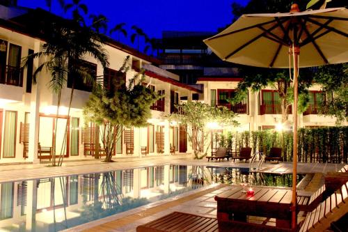 a pool with an umbrella next to a building at The Mantrini Chiang Rai in Chiang Rai