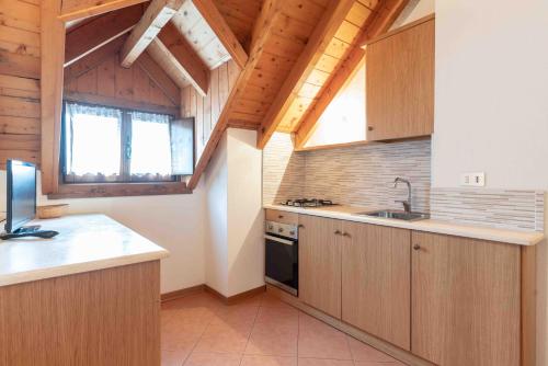 a kitchen with wooden cabinets and a sink at RESIDENCE-HOTEL CIMBRO in Mezzaselva