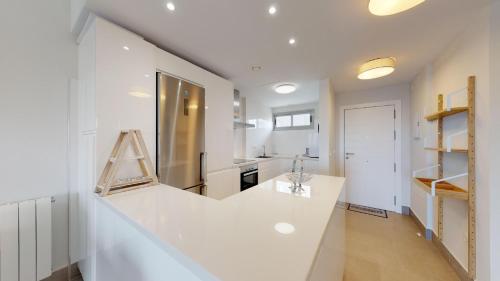 uma cozinha branca com uma grande bancada branca em Apartment Altos Del Rompido em El Rompido