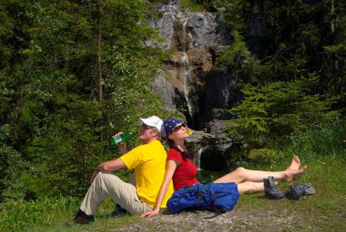 a man and woman sitting on the grass near a waterfall at Gästehaus am Graben in Reutte