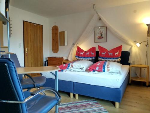 ロイタッシュにあるHaus am Wiesenrainのベッドルーム1室(赤い枕とテーブル付きのベッド1台付)