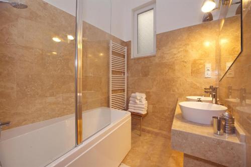 een badkamer met een bad, een wastafel en een douche bij The Stoned Loft-Budapest in Boedapest