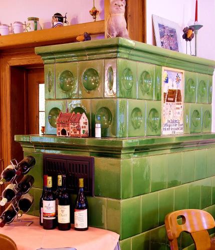 a green tiled fireplace with bottles of wine on it at Wildkräuter-Gasthof Linde in Löffingen