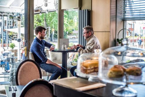 zwei Männer sitzen an einem Tisch in einem Restaurant in der Unterkunft N'ista Boutique Rooms Birkdale, Southport in Southport