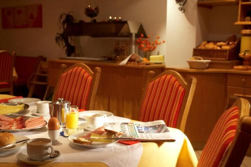 a table with food on it with red chairs at Gästehaus am Graben in Reutte