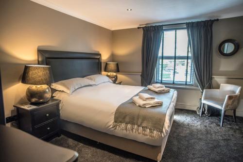 a bedroom with a bed and two lamps and a chair at N'ista Boutique Rooms Birkdale, Southport in Southport