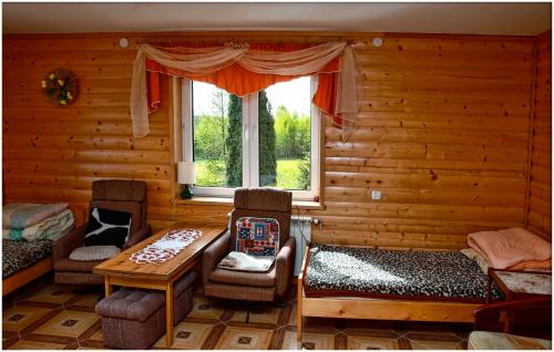 ein Wohnzimmer mit einem Tisch, Stühlen und einem Fenster in der Unterkunft Agroturystyka Na Skarpie in Wiżajny