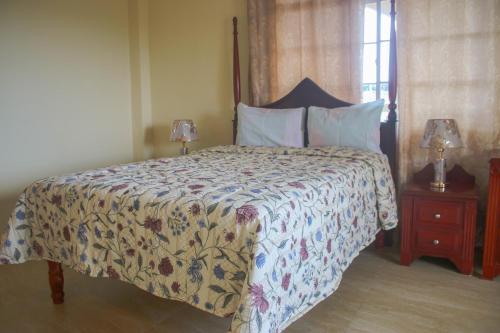 a bedroom with a bed with a floral bedspread and two lamps at Solet's Paradise Negril in Negril