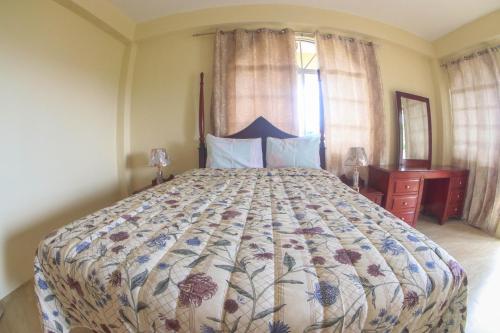 a bedroom with a large bed with a floral bedspread at Solet's Paradise Negril in Negril
