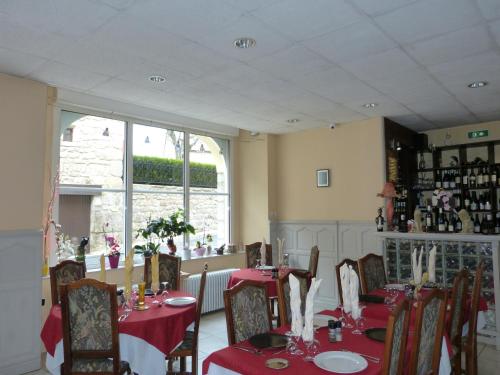 een eetkamer met tafels en stoelen met rode tafellakens bij le lion d'or in Saint-Chély-dʼApcher