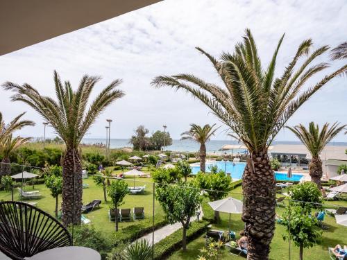 uitzicht op het zwembad en de palmbomen van het resort bij Marinos Beach Hotel in Platanes