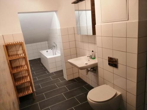 a white bathroom with a toilet and a sink at Ferienwohnungen Poppelvitz in Altefähr
