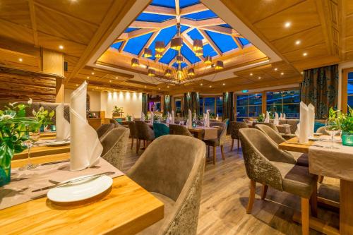 een eetkamer met tafels en stoelen en een kroonluchter bij Wohlfühlhotel Berwanger Hof in Obermaiselstein