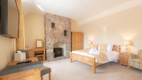 a bedroom with a bed and a stone fireplace at Lastra Farm Hotel in Amlwch