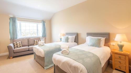 a bedroom with two beds and a couch and a window at Lastra Farm Hotel in Amlwch