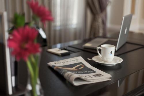 a desk with a laptop and a cup and a newspaper at Divan Erbil Hotel in Erbil