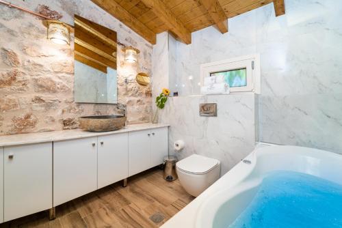 a bathroom with a tub and a toilet and a sink at Villa Zacharenia in Nikiana