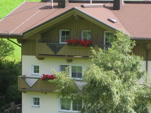 una casa con un balcón con flores rojas. en Haus Brigitta en Tux